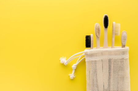 Zero waste concept. Set of eco natural bamboo toothbrushes in a cotton bag on a bright yellow background. Top view, copy space. Eco-friendly, no plastic.の写真素材