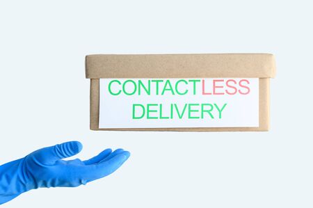 Contactless Safe Delivery Concept. Cardboard box levitates above a hand in a blue protective glove on a light background. Online shopping, staying at home during the coronavirus pandemic. Horizontal.の写真素材