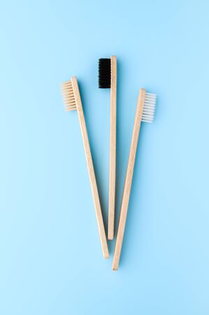 Zero waste and no plastic concept. Three eco friendly bamboo toothbrushes on a light blue surface. Top view, vertical orientation. Layout natural organic hygiene products.の写真素材