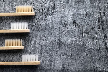 Zero waste and no plastic concept. Set of eco friendly bamboo toothbrushes on a dark gray surface. Top view, copy space, horizontal orientation. Layout natural organic hygiene products.の写真素材
