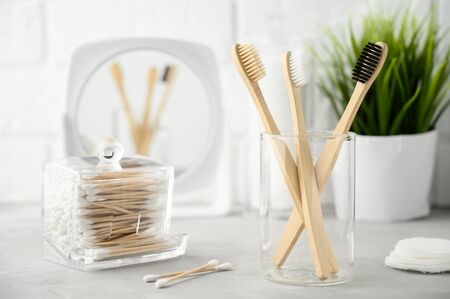 Without plastic concept. Eco friendly bathroom accessories. Bamboo toothbrushes, cotton pads and cotton buds on a light gray table. Zero waste. Copy space, Horizontal orientation.の写真素材