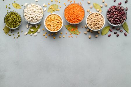 Various sources of vegetable protein: beans, lentils, peas, chickpeas, mung bean in bowls. A healthy balanced diet for vegans and vegetarians. Gray stone background. Top view, copy space.の写真素材