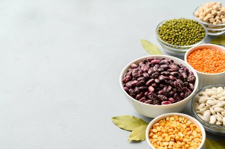 Various sources of vegetable protein: beans, lentils, peas, chickpeas, mung bean in bowls. A healthy balanced diet for vegans and vegetarians. Gray stone background. Copy spaceの写真素材