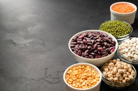Various sources of vegetable protein: beans, lentils, peas, chickpeas, mung bean in bowls. A healthy balanced diet for vegans and vegetarians. Dark stone background. Copy spaceの写真素材