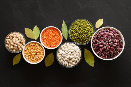 Various sources of vegetable protein: beans, lentils, peas, chickpeas, mung bean in bowls. A healthy balanced diet for vegans and vegetarians. Dark background. Top view.の写真素材