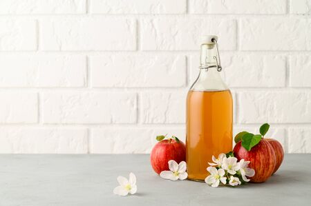 Homemade fermented kombucha drink in a glass bottle and fresh apples on a light gray stone table. A healthy probiotic drink. Copy space.の写真素材