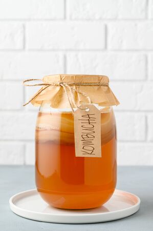 Homemade fermented kombucha tea in a glass jar on a background of a white brick wall. copy space, vertical orientationの写真素材