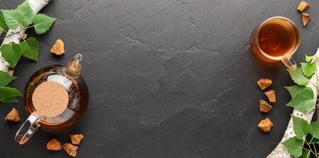 Chaga mushroom drink in a glass cup and teapot. Healthy drink. Top view with space for text, banner. Dark background.の写真素材