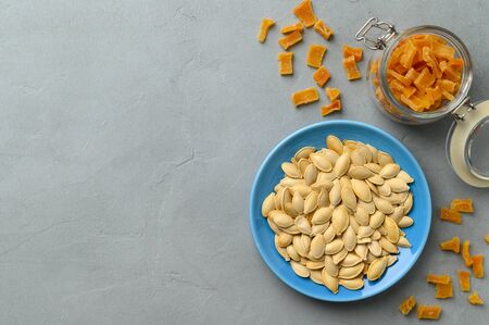 Dried pumpkin slices and seeds on a gray stone background. Candied pumpkin. Top view with copy space.の写真素材