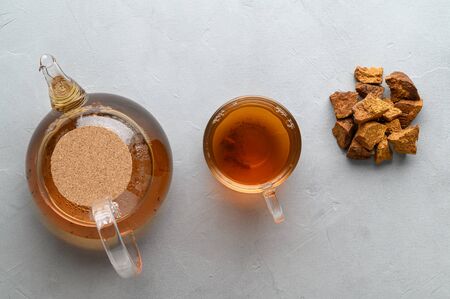 Chaga mushroom drink in a glass cup and teapot. Trendy healthy birch mushrooms. Top view. Light gray stone background.の写真素材