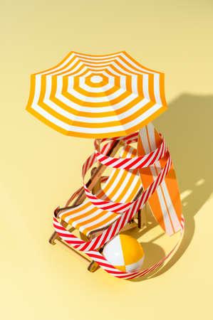 Deck chair, umbrella, surfboard and ball are wound with protective signal tape on the beach. Concept of closed beach. Miniature minimalistic composition. Vertical orientationの写真素材