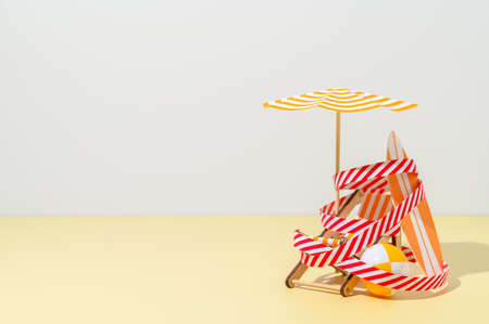 Deck chair, umbrella, surfboard and ball are wound with protective signal tape on the beach. Concept of closed beach. Miniature minimalistic composition. Copy spaceの写真素材