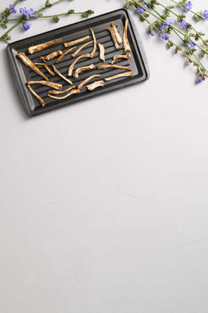 Healthly food. Dried chicory roots on a baking sheet. Light gray concrete background. Top view, copy space.の写真素材