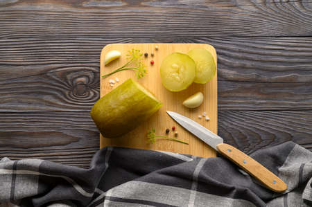 Healthy fermented vegan food. Sliced fermented pickled cucumber and spices on a cutting board. Rustic wooden background. Top view.の写真素材