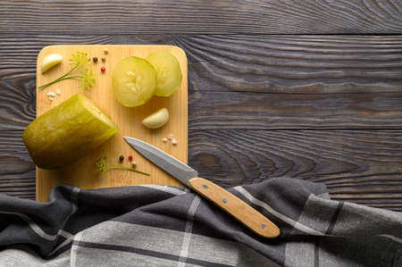 Healthy fermented vegan food. Sliced fermented pickled cucumber and spices on a cutting board. Rustic wooden background. Top view, copy space.の写真素材