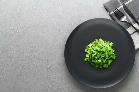 Sliced green onions in a black plate with a knife and fork. Allium nutans onion. Top view, copy...