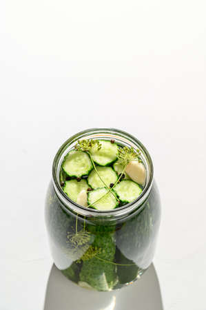 Healthy vegan food. Homemade fermented cucumbers with garlic, dill and pepper in a glass jar. Light background. Copy space, top view, hard light.の写真素材