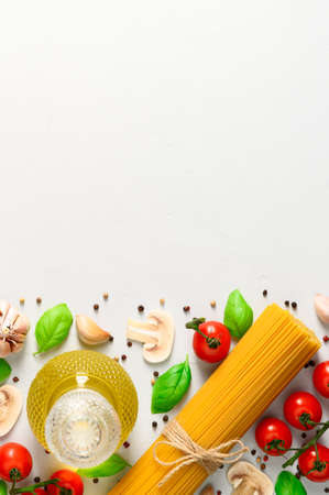 Spaghetti and ingredients for cooking Italian pasta with mushrooms on a light gray background. Top view with copy space, vertical orientation.の写真素材