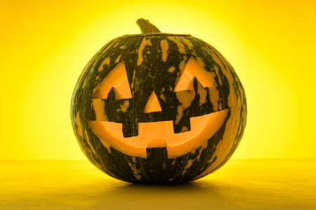 Happy Halloween. Funny glowing pumpkin Jack-o-lantern on a yellow background. Backlightの写真素材