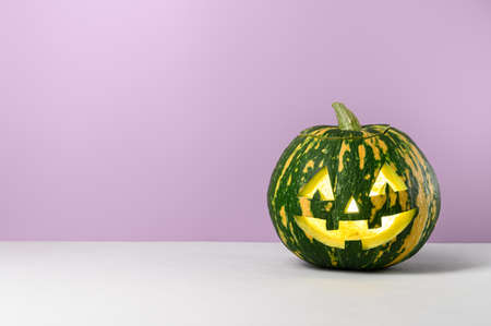 Funny smiling Halloween pumpkin on a purple background. Halloween symbol. Minimalistic composition. Copy spaceの写真素材