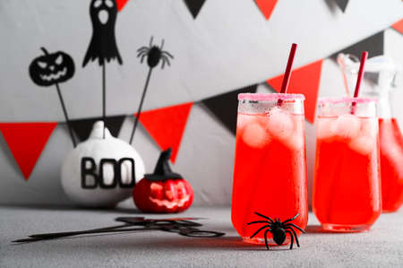Iced pumpkin cocktails in glasses decorated with scary faces on a gray table. DIY Halloween Party decoration on the wall. Halloween mocktails.の写真素材