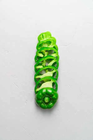 Eco food concept. Top view of sliced green peppers on gray background. Minimal style. Flat lay, vertical orientationの写真素材
