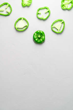 Eco food concept. Top view of sliced green peppers on gray background. Minimal style. Flat lay, vertical orientation, copy spaceの写真素材
