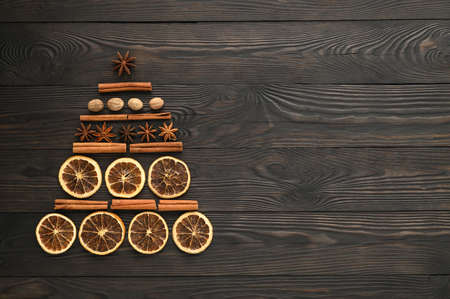 Alternative Christmas tree. Top view of Christmas tree made from anise star, cinnamon sticks, orange dry, and nutmeg on a dark wooden background. Copy space, flat lay.の写真素材