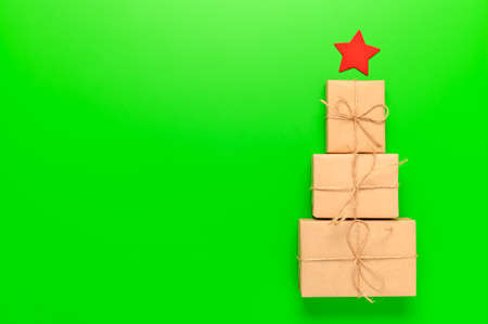 Alternative Christmas tree made from gift boxes with a red star on a green background. Space for...