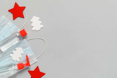 Christmas era covid concept. Medical protective masks, sanitizer bottles and Christmas decorations on a gray background. Flat Lay, copy space.の写真素材