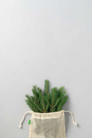 Bouquet of fir branches in fabric eco bag on gray background. Minimal Christmas zero waste concept. Flat lay, Top View, copy space.の写真素材