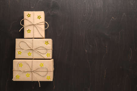 Alternative Christmas tree made from gift boxes with a red star on a dark brown background. Copy Space, Flat lay.の写真素材