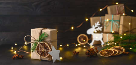 Christmas zero waste concept. Eco friendly packaging gifts in kraft paper on a dark wooden table. DIY gifts, eco decor. Copy space, banner.の写真素材