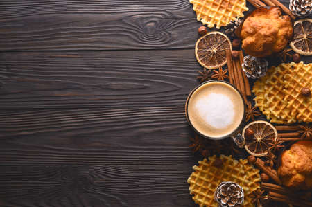 Cup of hot coffee, cookies and spices on wooden rustic background. Stylish cozy winter flat lay. Seasonal holidays concept. Top view, copy spaceの写真素材