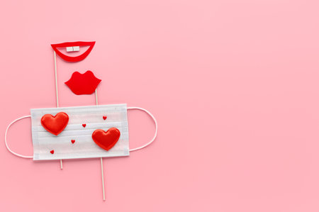 New normal Valentine's Day. Medical face mask decorated with hearts, red paper party accessories glasses, lips on pastel pink background. Concept Homosexuality, lesbian love. Top view, flat layの写真素材