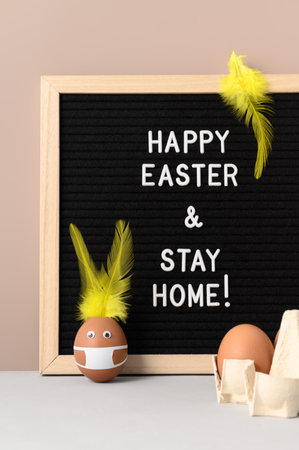 Easter holiday concept 2021. Easter bunny made from egg wearing protective face mask, and black felt...