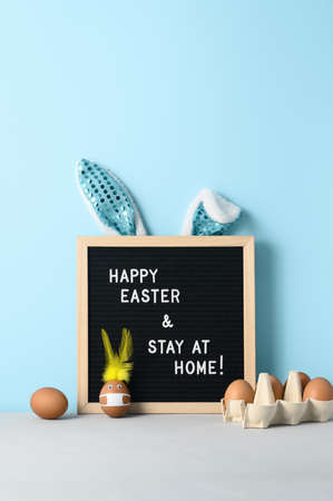 Easter holiday concept 2021. Easter bunny made from egg wearing protective face mask, and black felt...
