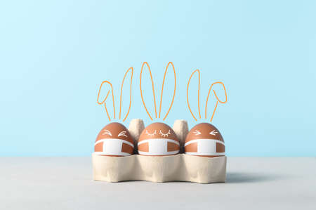 New normal Easter holiday concept. Easter cute bunnies made from eggs wearing protective face masks...