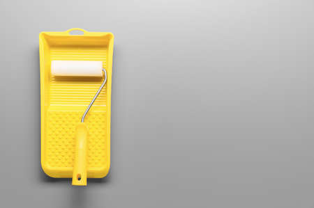 Colors of the year 2021 Ultimate Gray and Illuminating Yellow. Bright Yellow painting tray cuvette and paint roller on gray background. Renovation concept. Minimalistic composition with copy spaceの写真素材