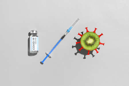 Coronavirus vaccination creative concept. Vial vaccine, medical syringe, and kiwi fruit in form...