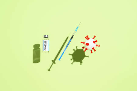 Coronavirus vaccination concept. Vial vaccine, medical syringe, and white ball in form virus,...