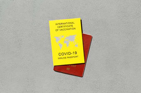 Immune passport, as proof vaccinated against, a requirement for international travel. Yellow Certificate of Vaccination on gray background. Top viewの写真素材
