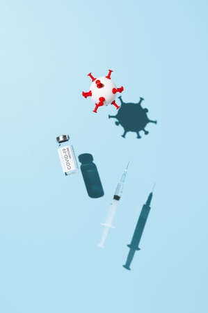 Coronavirus vaccination concept. Vial vaccine, medical syringe, and white ball in form virus, levitating over pastel blue background. Top viewの写真素材