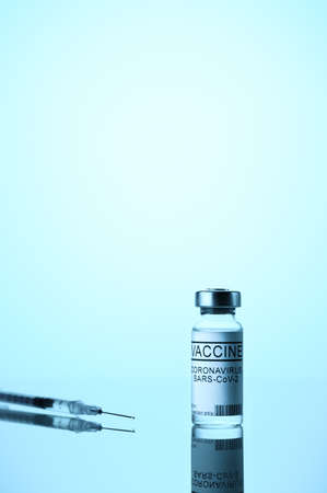 Coronavirus vaccination concept. Vial COVID-19 vaccine, and medical syringe on blue background. Space for textの写真素材