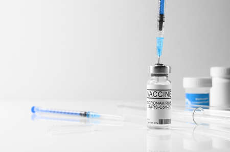 Coronavirus vaccination concept. Filling syringe with COVID-19 vaccine on white background. Vial and...