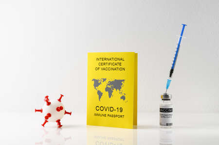 Traveling Immune passport, as proof vaccinated against Covid-19. Yellow International Certificate of Vaccination, syringe, vial with vaccine on white backgroundの写真素材