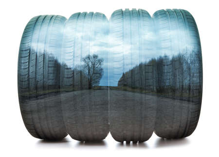 Double exposure of a car tire close-up and suburban asphalt road in the forest. Horizontal...
