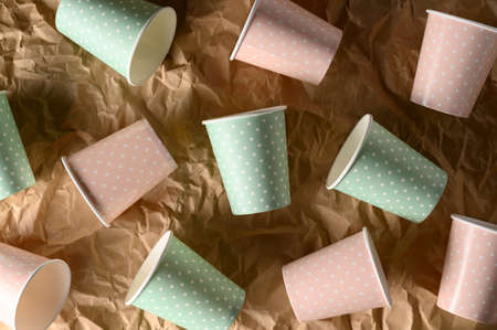 From above of arranged color paper cups on crumpled craft paper. Plastic-free concept, biodegradable...