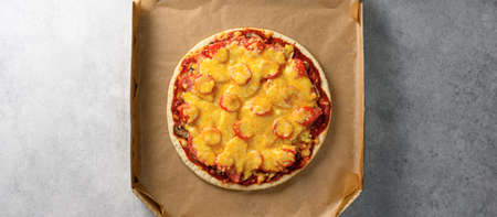 Top view of hot tasty homemade pizza with green basil leaves on the grey concrete background. Italian pizza in a cardboard box. With copy space for text. Flat lay, bannerの写真素材