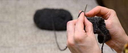 Close-up of female hands knit handmade clothes in the room. Knitting hobby.の写真素材